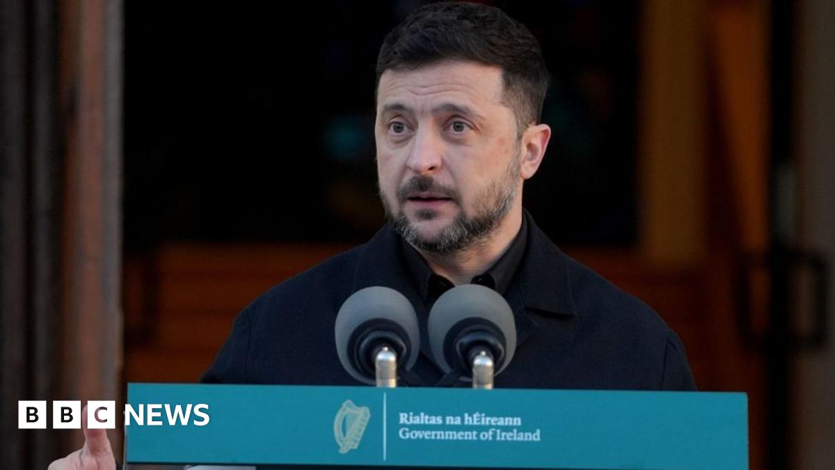 Volodymyr Zelensky and his wife Olena Zelenska disembark from plane stairs towards the runway at Dublin Airport. On the side of the plane is a yellow and blue Ukrainian symbol.