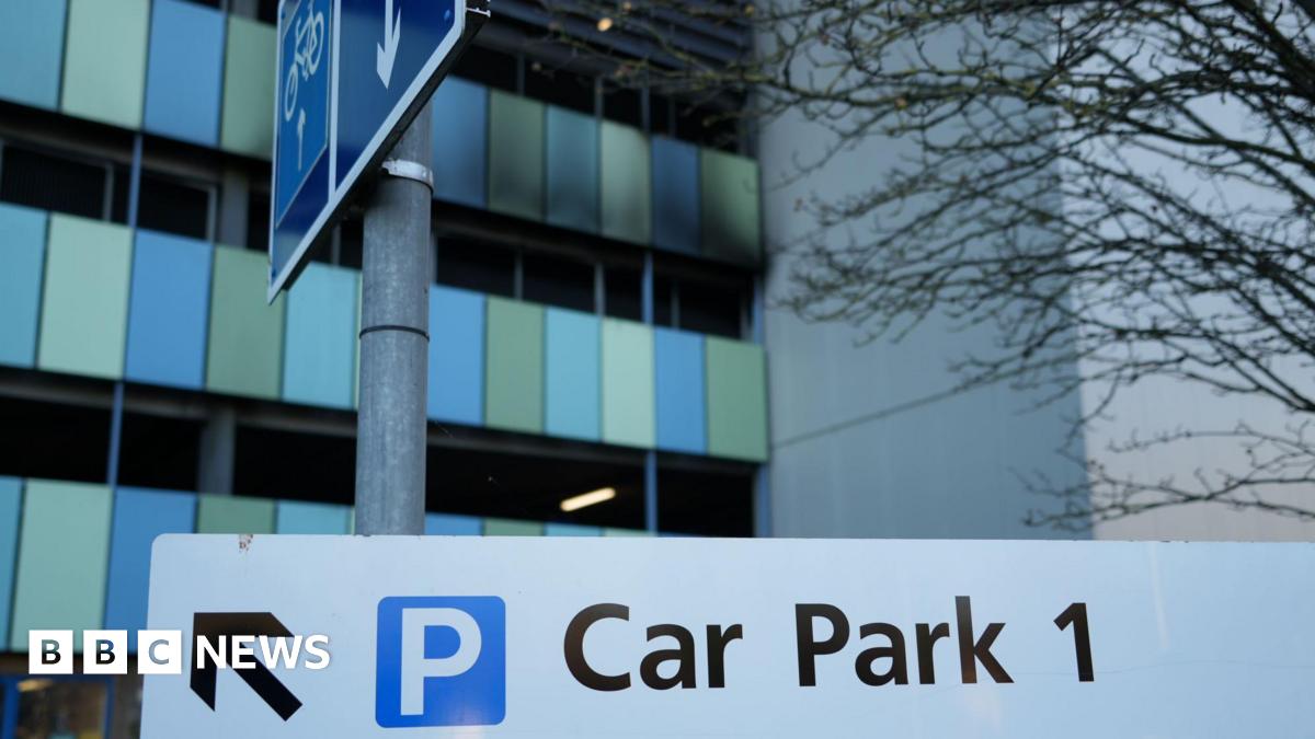 Part of the outside of a car park shows black charring on green and blue panels and a wall.