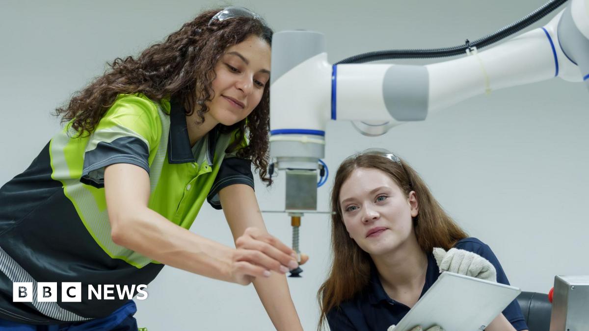 Female engineers performing collaborative robotic operation training in smart factory one controlling robotic machine other observing process teamwork focus in hands-on automation skill lab