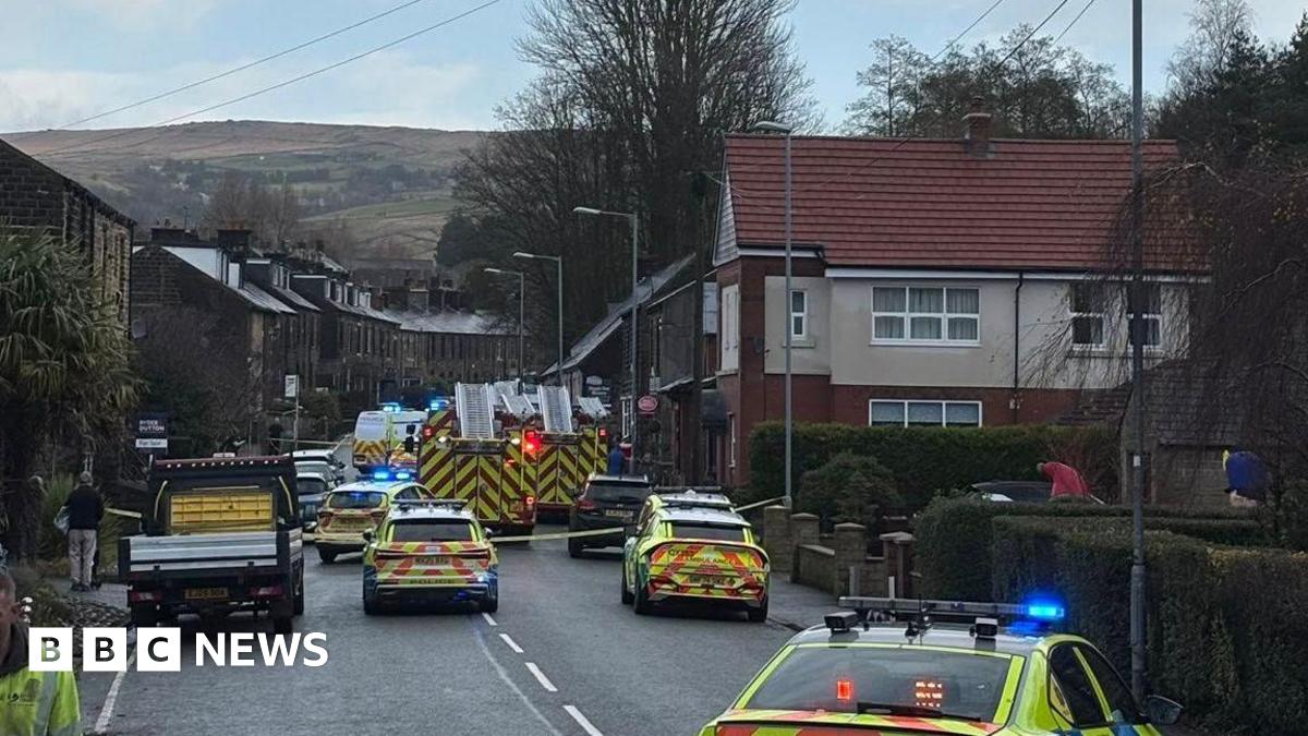 A busy road off Dorset Avenue with multiple police cars, and multiple fire engines. The road is sectioned off by yellow police tape.