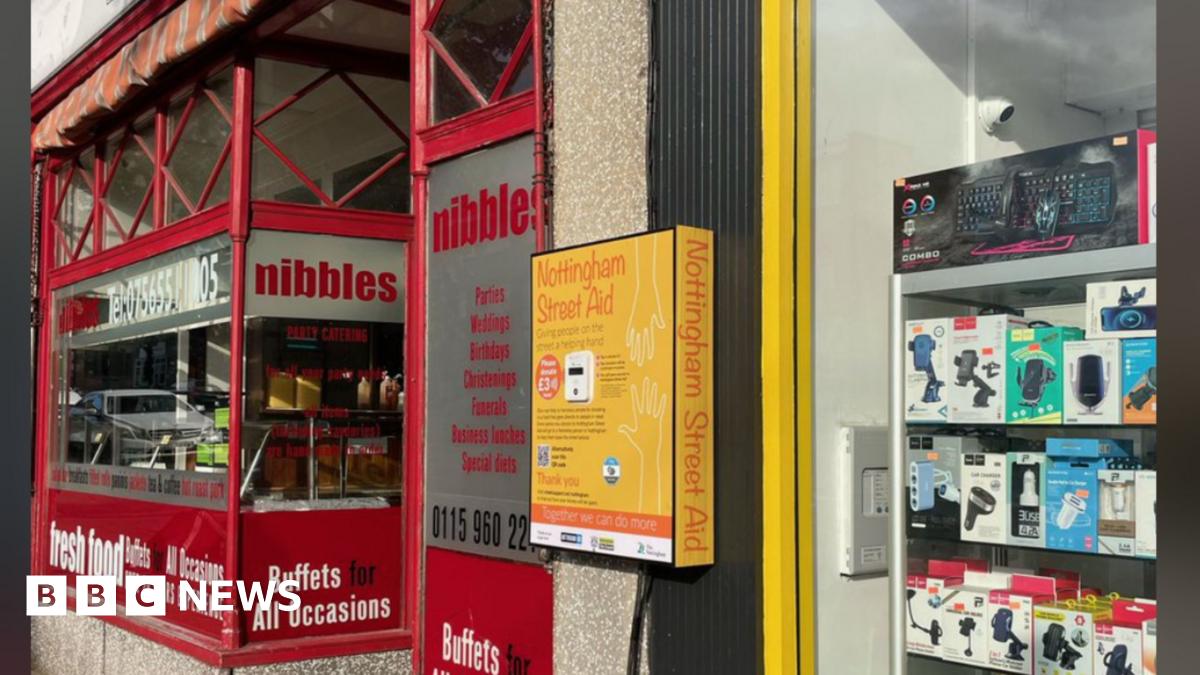 A yellow donation point mounted on a wall outside a high street shop