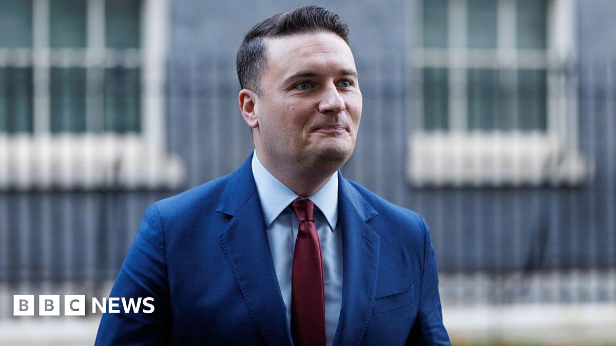 Health Secretary Wes Streeting wearing a blue suit and red tie leaves Downing Street on 2 December 2025.