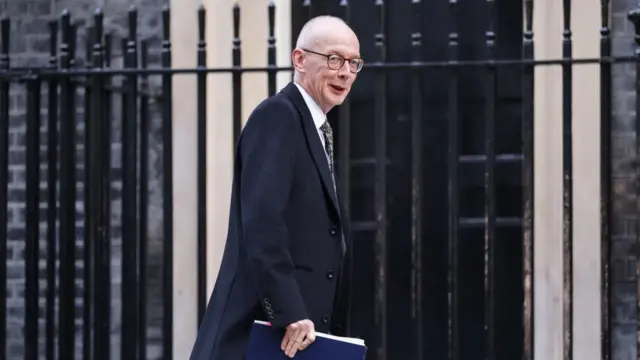 Pat McFadden arrives in Downing Street , holding a navy folder