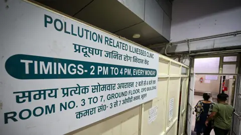 Getty Images A view outside the pollution-related illnesses clinic at Delhi's RML Hospital - which was one of the six that were part of the government study, based on which it submitted its data to the parliament. A large board reads out timing, room numbers, etc at the centre. A man and a woman can be seen entering one of the rooms