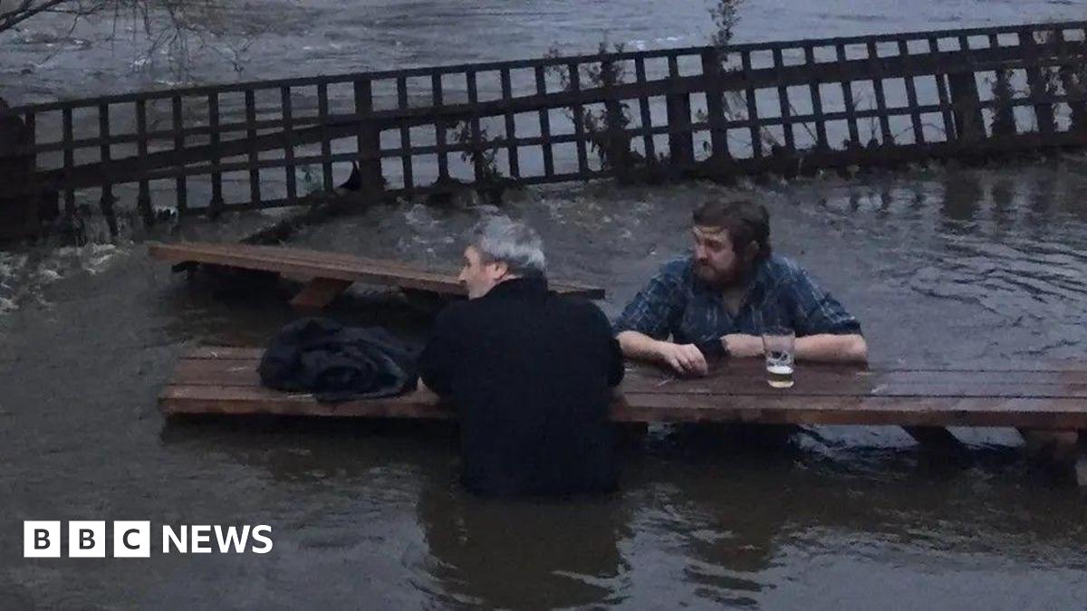 Two men sitting at park benches with beer. They are surrounded by water, which goes up to their waist.