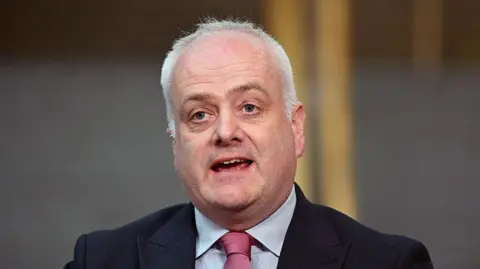Getty Images A man with short white hair wearing a dark suit is speaking in Holyrood