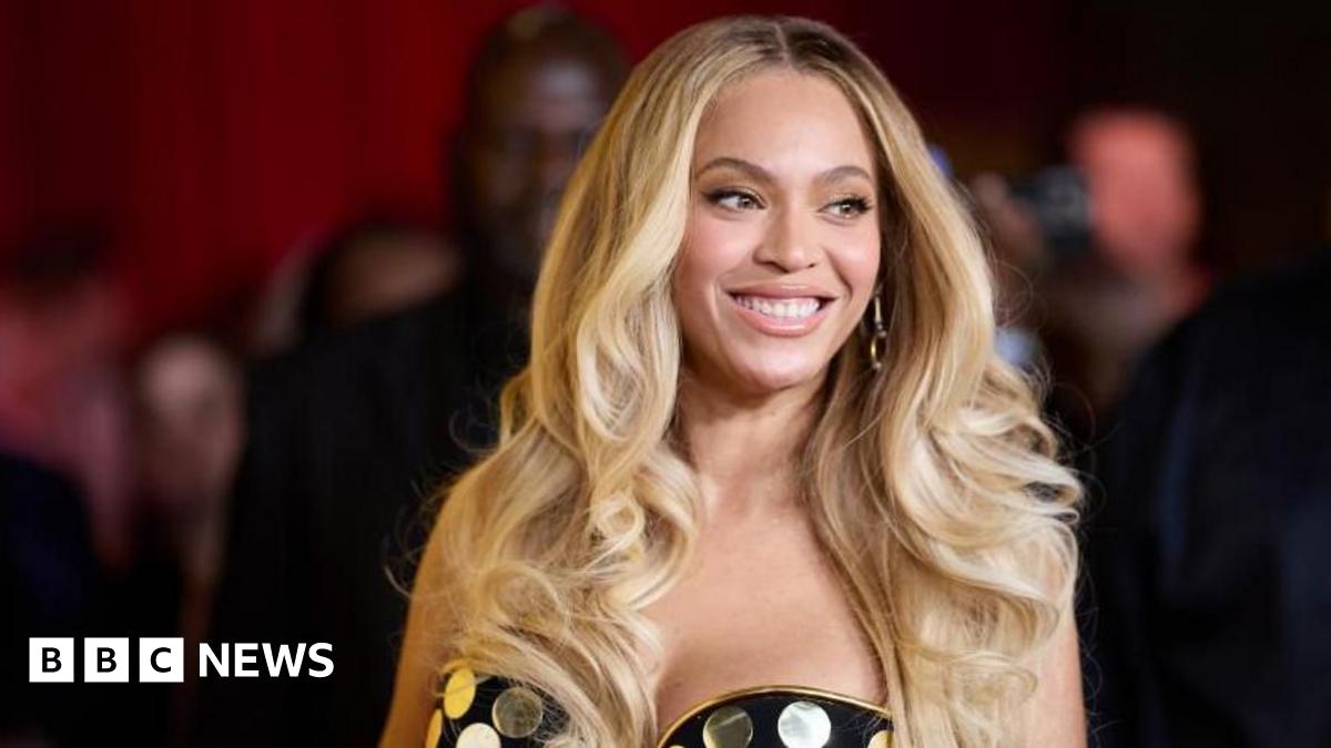 Beyonce has long blonde hair and a strapless gold and black spotted dress