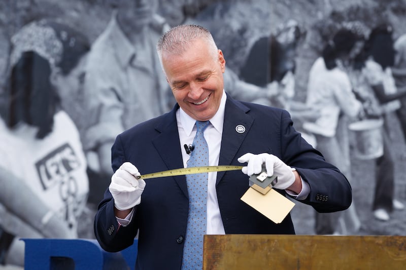 BYU President C. Shane Reese holds up a tape measurer included in a 1975 time capsule, as he unboxes items during a Founder's Day event on Oct. 16, 2025, on Brigham Square in Provo, Utah.