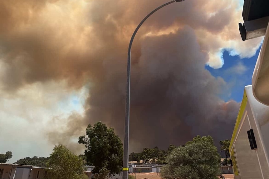 Dark smoke billows across a skyline