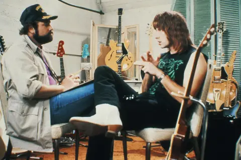 Authorized Spinal Tap LLC/Shutterstock Rob Reiner as on-screen director Marty DiBergi interviewing Christopher Guest as Nigel Tufnel surrounded by guitars in a scene from This Is Spinal Tap