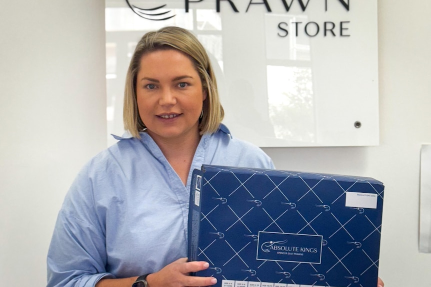 A women holds a box of seafood and smiles