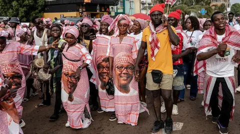 AFP via Getty Images Supporters dressed in gowns bearing Umaro Sissoco Embaló's face march in the streets