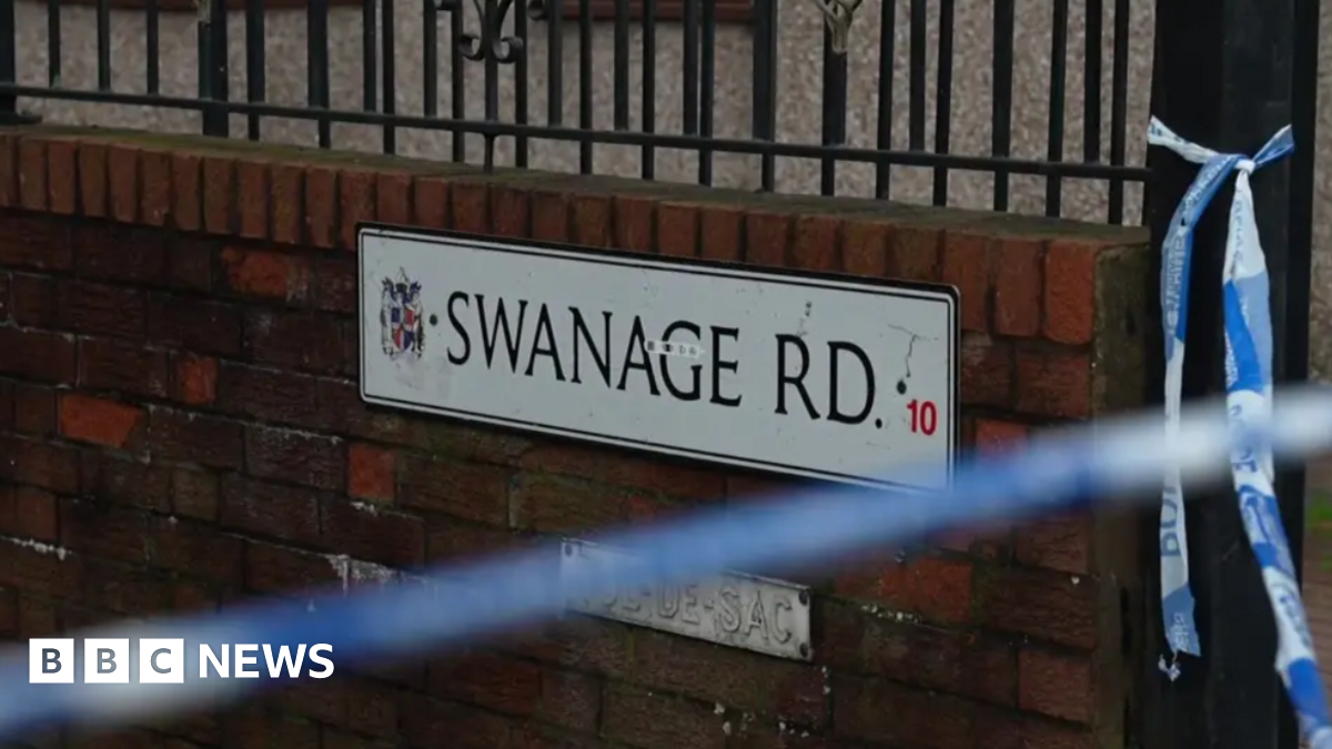 A close up of road sign on a brick wall, which says Swanage Road. There is police tape near the sign