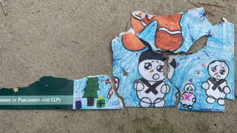 BBC Remnants of a christmas card meant for "Members of Parliament and CLPs" showing childrens' drawings of snowmen, presents under a christmas tree and a sugar cane 