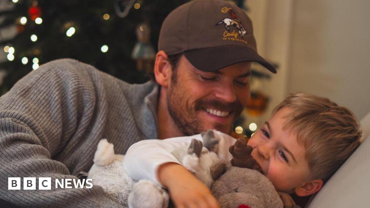 Ryan smiling and tickling his giggling young son Leo on the sofa
