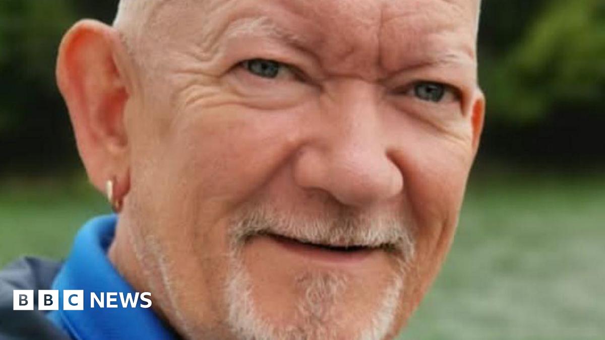 William Chapman, 58, who is bald, with a white goatee and wears a gold ring in his right ear, smiles at the camera.