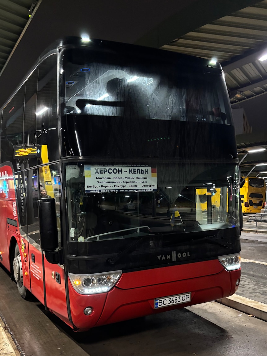 A large double-decker bus with a sign in Ukrainian on the front.