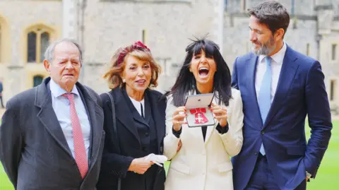 PA Claudia Winkleman with her dad, mum and husband celebrating her MBE