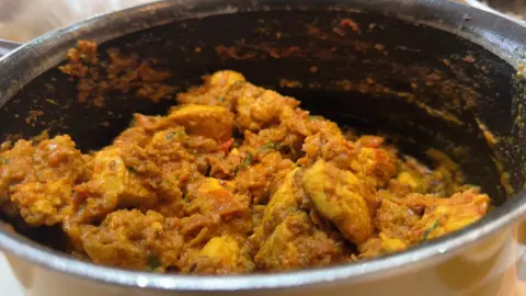Chicken curry shows pieces of meat with spices in a curry sauce