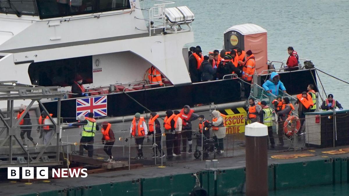 A group of people in life jackets being brought off a boat into a docking area