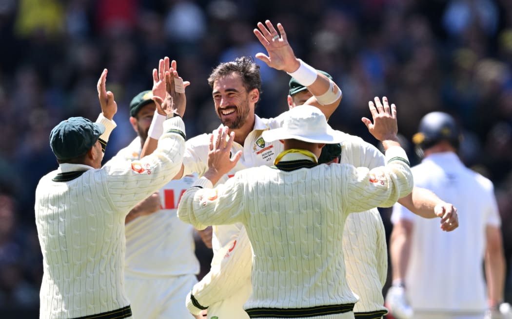 Mitchell Starc of Australia (C) celebrates with teammates after taking the wicket of England's Zak Crawley.