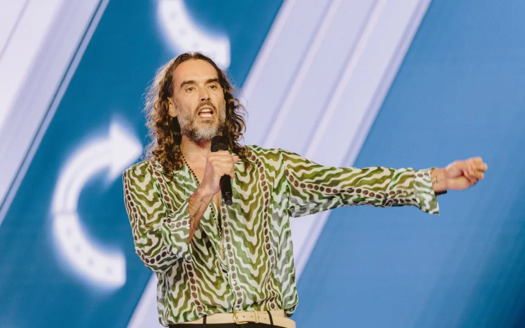 English comedian and actor Russell Brand speaks during Turning Point's annual AmericaFest conference, in remembrance of late right-wing political activist Charlie Kirk, in Phoenix, Arizona on December 18, 2025.