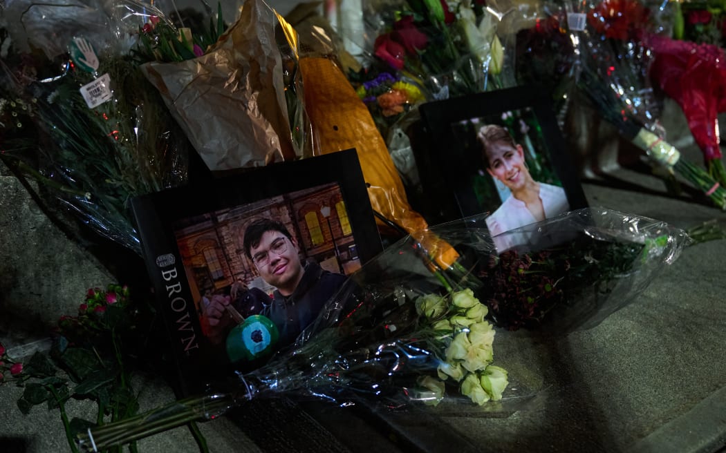 Framed photos of mass shooting victims Mukhammad Aziz Amurzokov and Ella Cook are seen at a makeshift memorial near Brown University in Providence, Rhode Island, on December 15, 2025. A gunman remained at large after a weekend mass shooting at elite Brown University left two dead and nine wounded, with US authorities releasing new footage of a masked 
