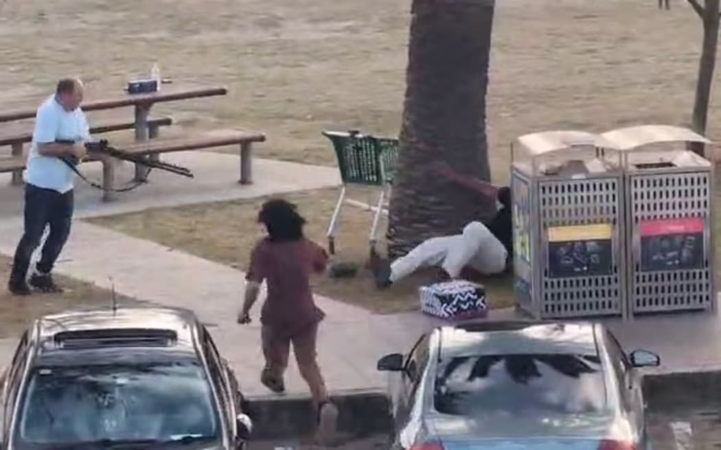 The man points the weapon at the now disarmed Bondi gunman.