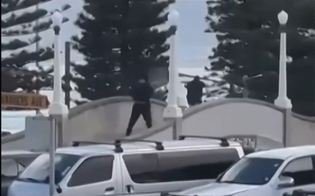 This screen grab made from UGC handout video footage courtesy of Timothy Brant-Coles shows two gunmen dressed in black firing multiple shots on a bridge at Bondi Beach in Sydney on December 14, 2025. Australian police said two people were in custody following reports of multiple gunshots on December 14 at Sydney's famed Bondi Beach, urging the public to take shelter. (Photo by Handout / various sources / AFP) / NO USE AFTER DECEMBER 24, 2025 09:47:07 GMT - NO USE AFTER DECEMBER 24, 2025 09:47:07 GMT - RESTRICTED TO EDITORIAL USE - MANDATORY CREDIT "AFP PHOTO /  COURTESY OF TIMOTHY BRANT-COLES" - HANDOUT - NO MARKETING NO ADVERTISING CAMPAIGNS - DISTRIBUTED AS A SERVICE TO CLIENTS - NO ARCHIVE /