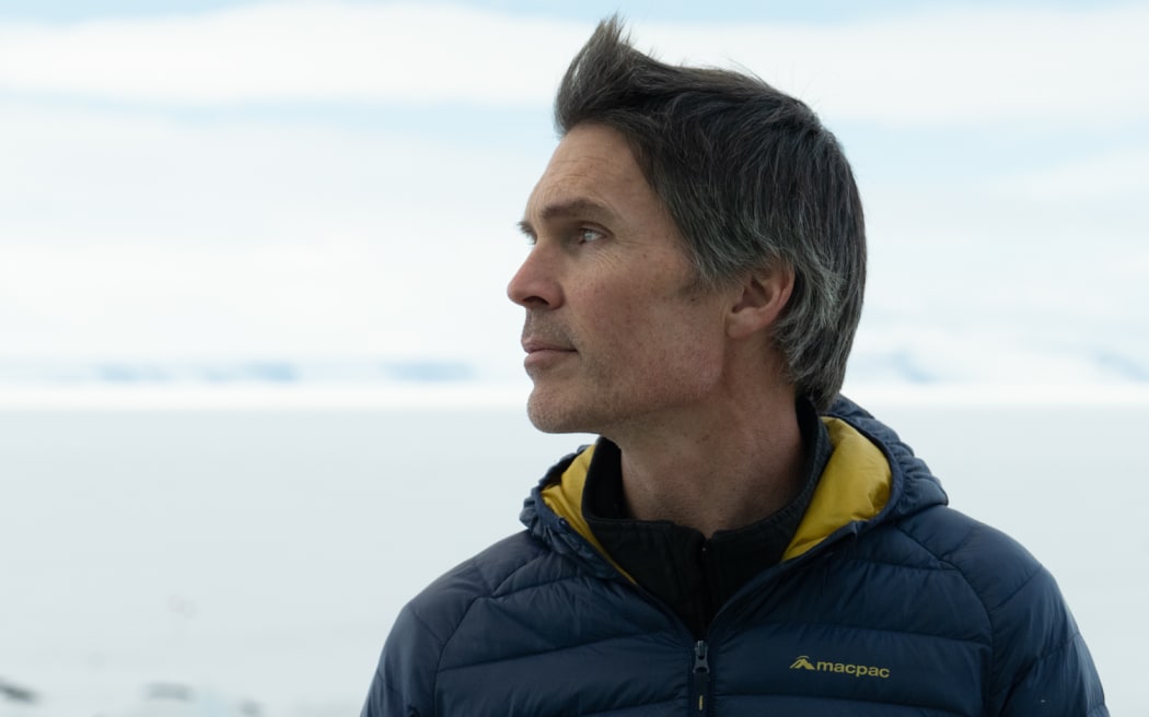 A head and shoulders portrait of Huw Horgan, dressed in warm clothing, standing against the white snow and ice of Antarctica.