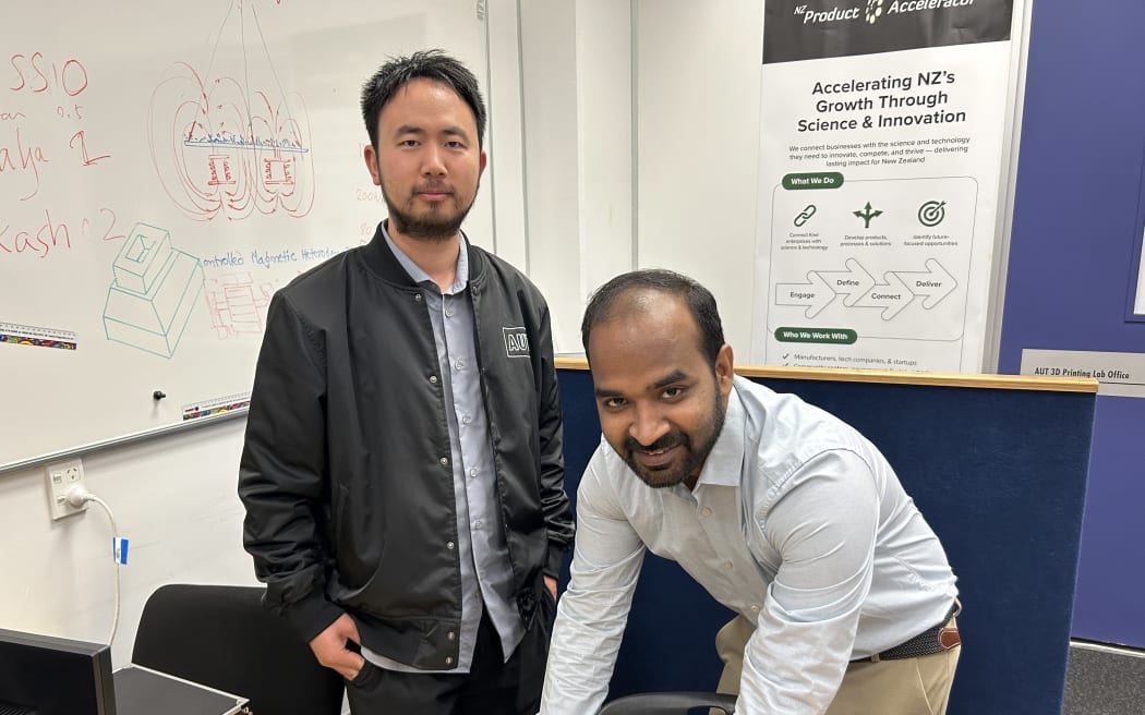 Photo shows two men smiling at camera.