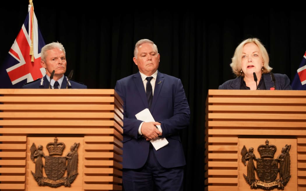Public Services Minister Judith Collins speaks after a damning report into police conduct, with Police Commissioner Richard Chambers and Police Minister Mark Mitchell in the background.