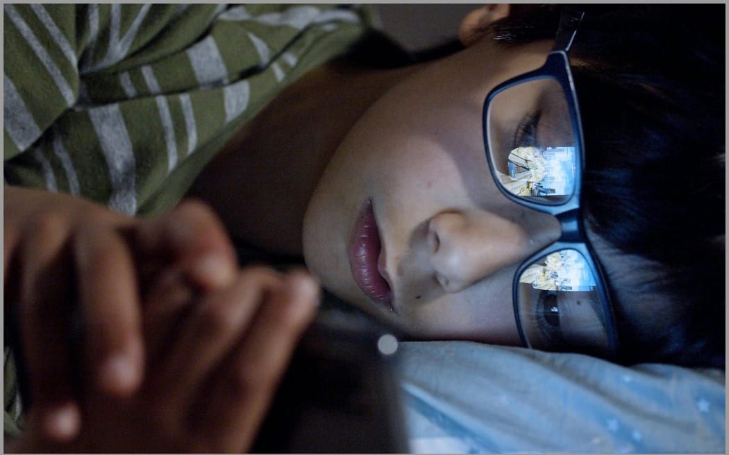 Image of boy holding a phone lying down