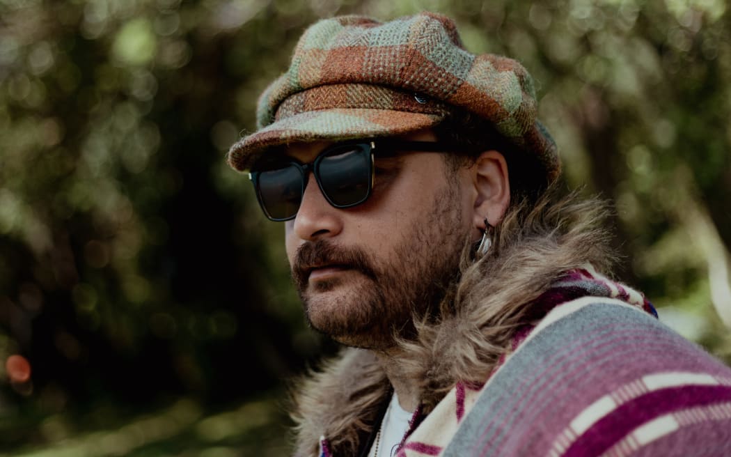 A man wearing sunglasses and a tartan hat is looking out to the left. Text reads, 