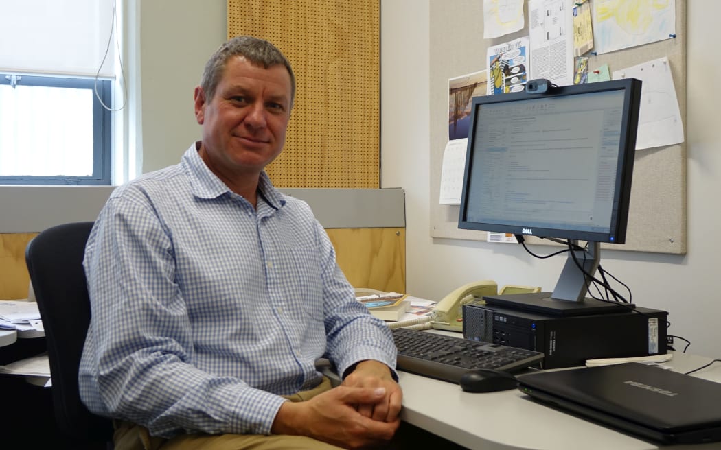 Professor sits in front of screen in his office