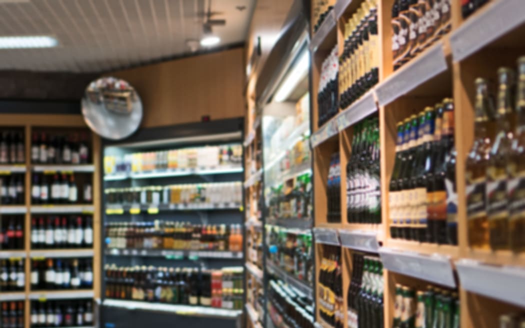 Blurred image of shelves with alcoholic drinks in supermarket.