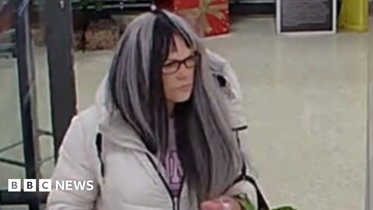 Rachael Cole wearing a white and black wig and glasses as she walks around a supermarket.