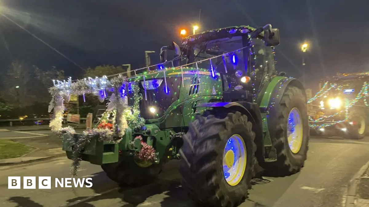 A green tractor covered in Christmas lights