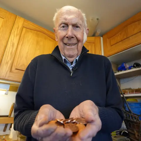 Richard Larn holding some coins he recovered from a shipwreck 