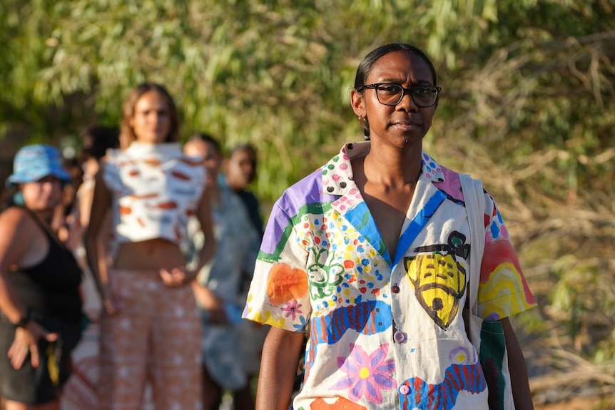 a woman with glasses and a colourful patterned shirt 