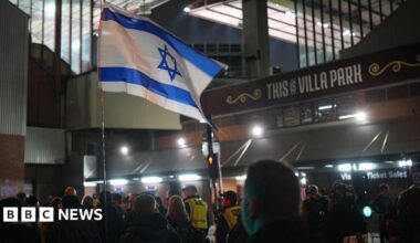 An Israeli flag held by pro-Israeli supporters outside Villa Park ahead of the game on 6 November 2025. It is night and police are escorting them