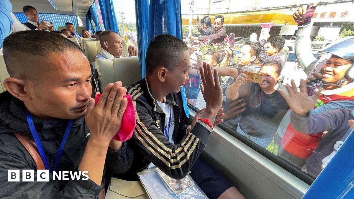 Cambodian soldiers, who had been captured by Thai soldiers in July, gesture to well-wishers from a bus after their release, near a checkpoint along the border with Thailand