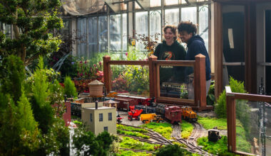 Two adults look at model trains in the Brookside Gardens conservatory