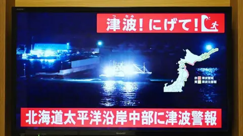 AFP via Getty Images A TV screen shows messages in Japanese which say "Tsunami! Run!" and "Tsunami warning issued for central Hokkaido's Pacific Coast".