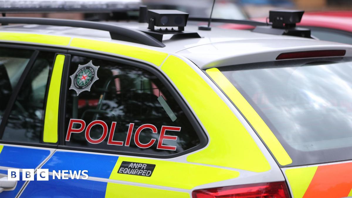 Blue, yellow and red vehicle with red police label on the window and PSNI crest.