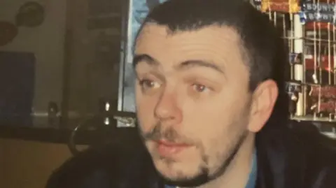 Alison Mark Jenner, pictured by Alison, in a building. He wears a dark jacket. 