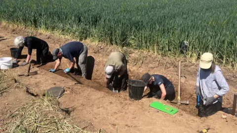 AOC Archaeology Group A group of archaeologists in a trench in a field during the excavation of the lost medieval villages.