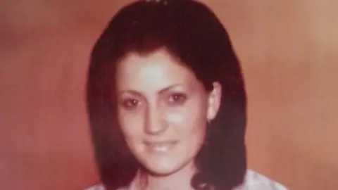 Family A picture of an old photo of Jean Smyth-Campbell. She is a young woman with short, brown hair. She is smiling at the camera.