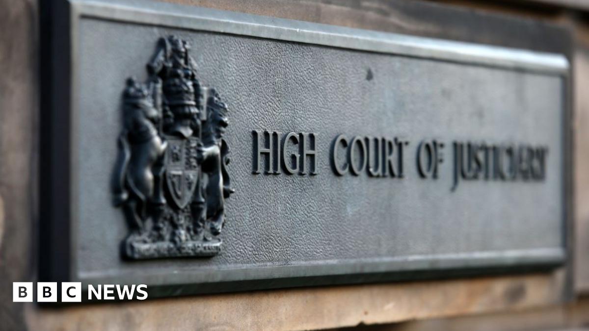 A metal sign on the wall of the High Court in Edinburgh which reads High Court of Justiciary