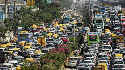 AFP via Getty Images Commuters wait in a traffic jam along a road leading to the Yelahanka Air Force Station in Bengaluru on 14 February, 2025. 